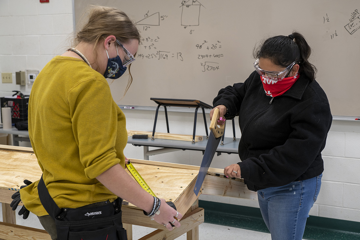 Two female students work together on a construction project
