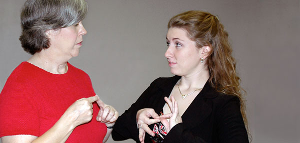Two women communicating with each other using sign language.