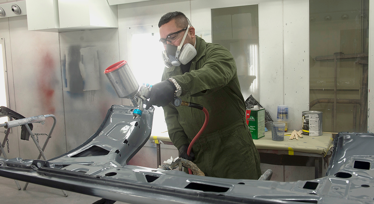 Autobody students working on a car door.