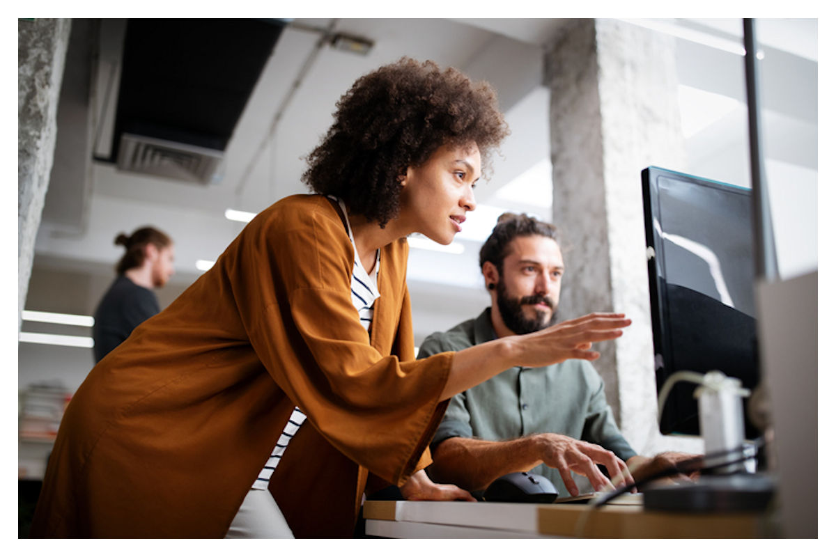 Woman helps co-worker at computer