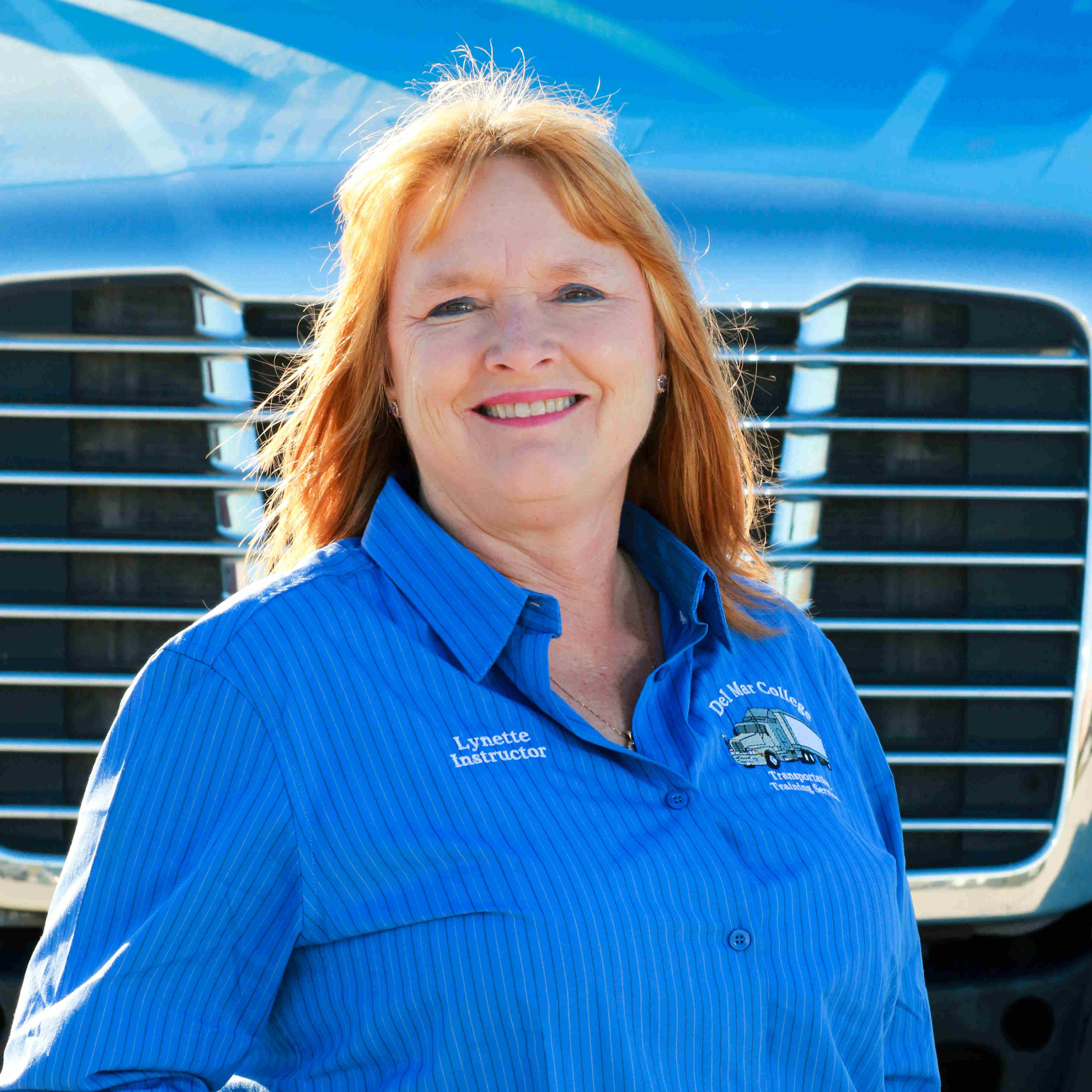 Lynette Redding Cervantes in front of an eighteen wheeler truck.