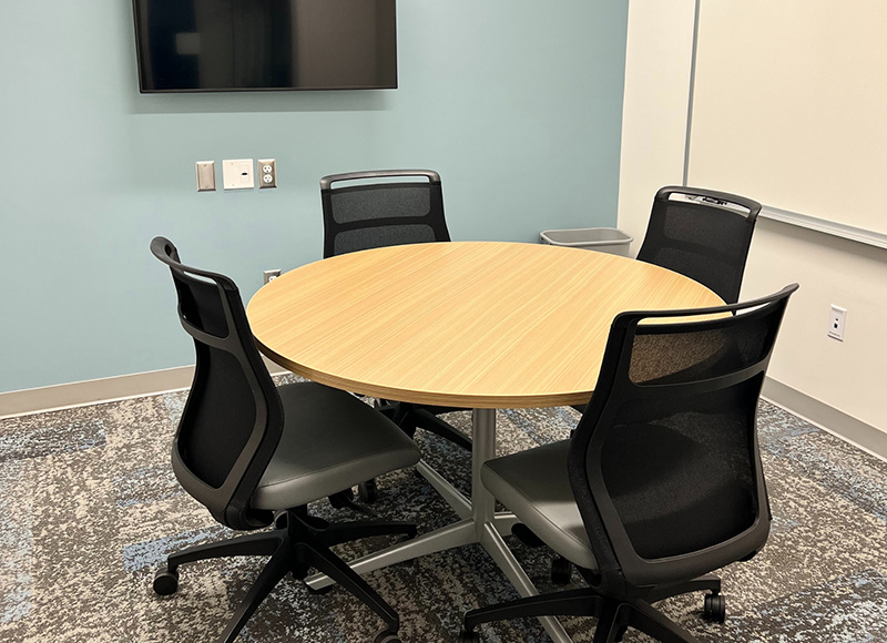 Study room with a table and chairs and a computer screen on the wall