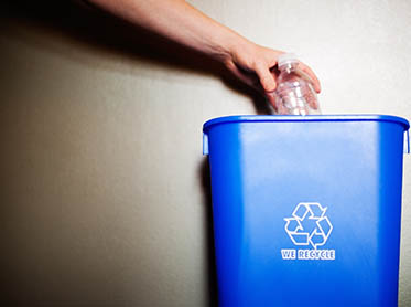 A blue recycle bin placed against a wall