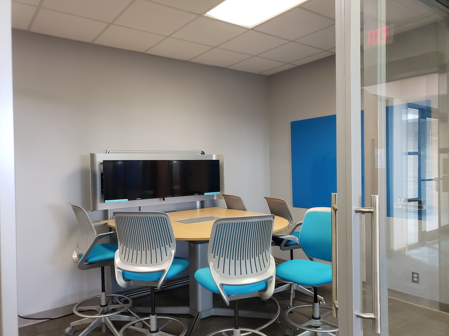 Mediascape style group study room with table/chairs, two monitors, and a dry erase board.