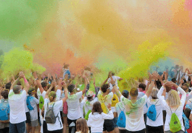 A group of people in a crowd at a run with colored smoke in the air