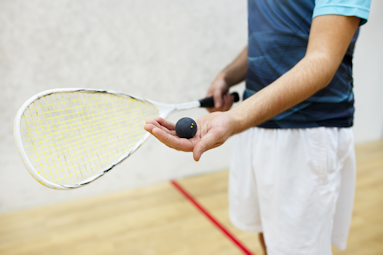 Guy holding a racquet and ball